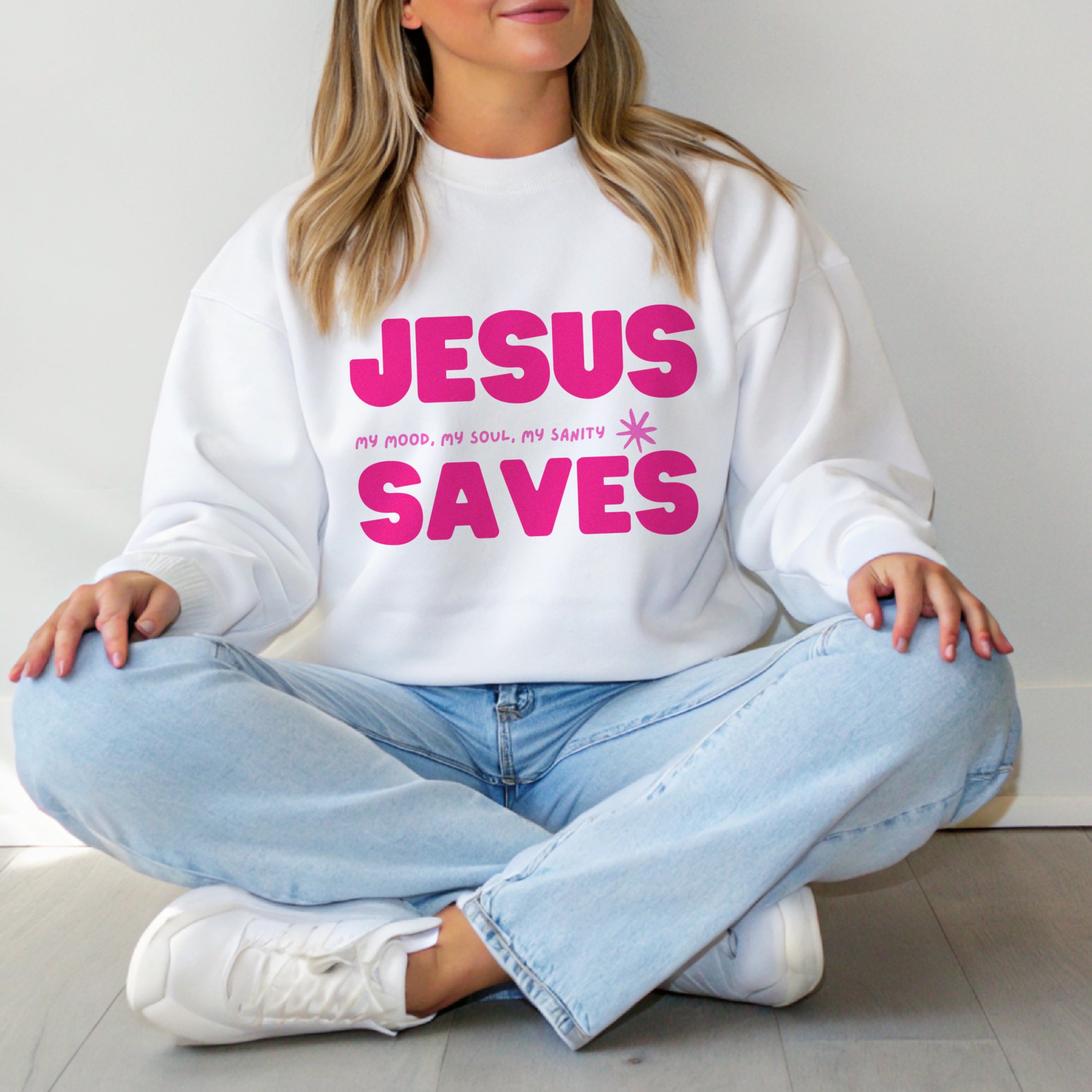 Woman wearing Jesus Saves pink crewneck sweatshirt with jeans, cozy Christian fashion for everyday faith