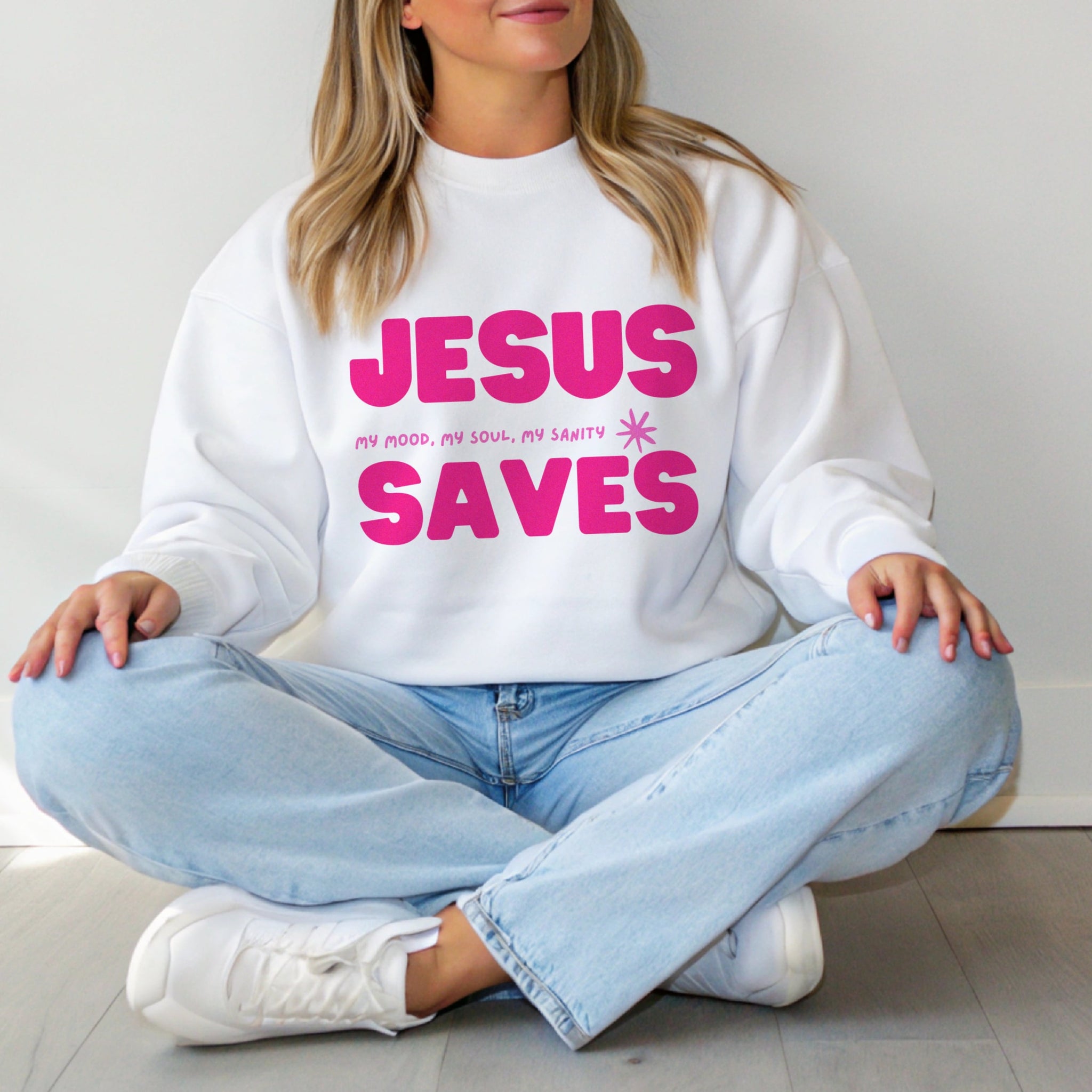 Woman wearing Jesus Saves pink crewneck sweatshirt with jeans, cozy Christian fashion for everyday faith