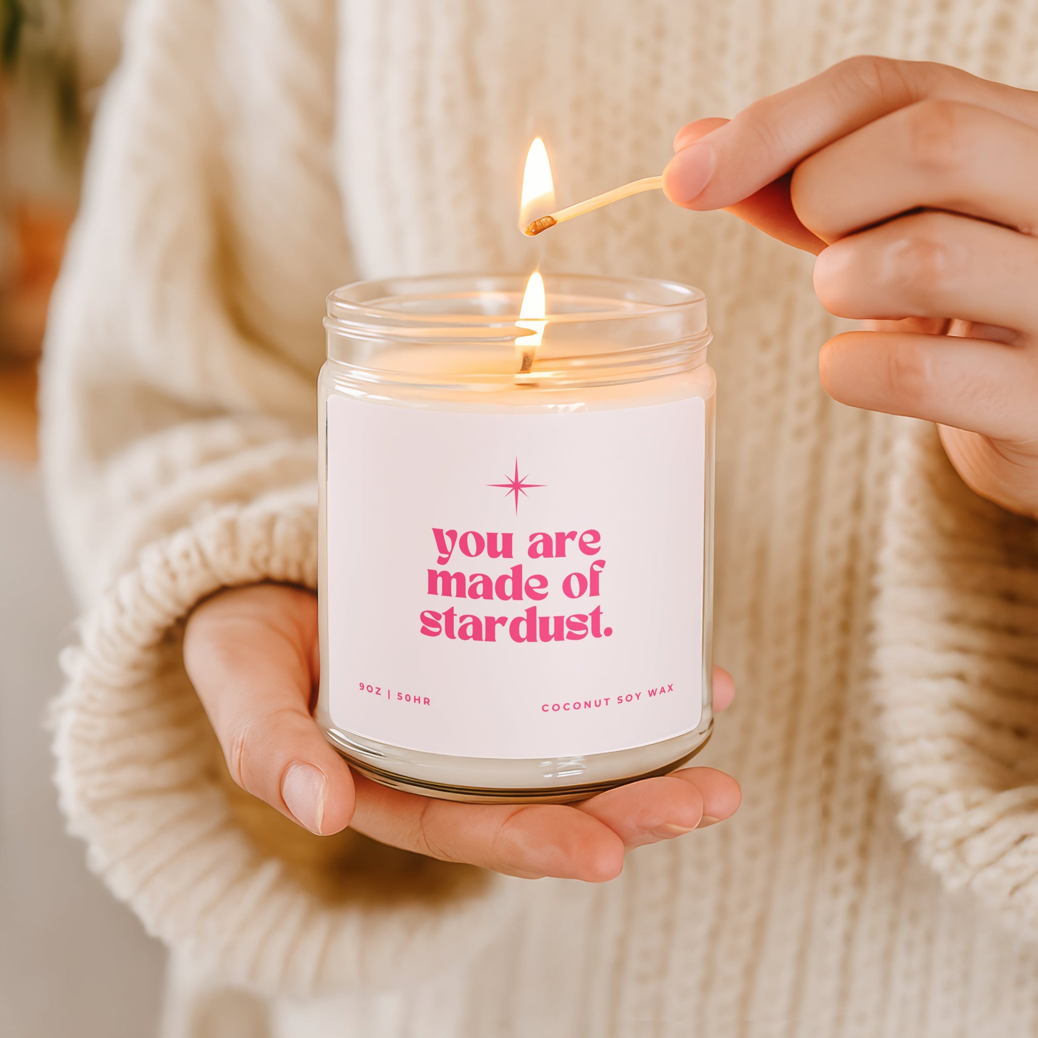 Person lighting a candle with pink 'you are made of stardust' text